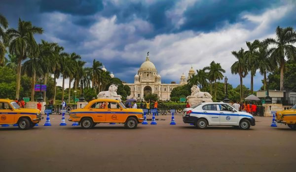 Hourly Rental on Thripthi Holidays Vibrant city scene with taxis and Victoria Memorial in Kolkata, India.