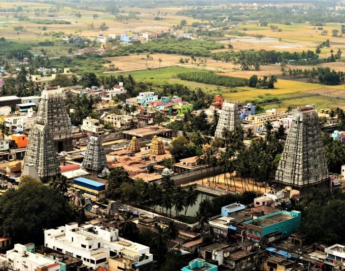 Aerial view of a historic temple complex surrounded by lush fields and colorful buildings.