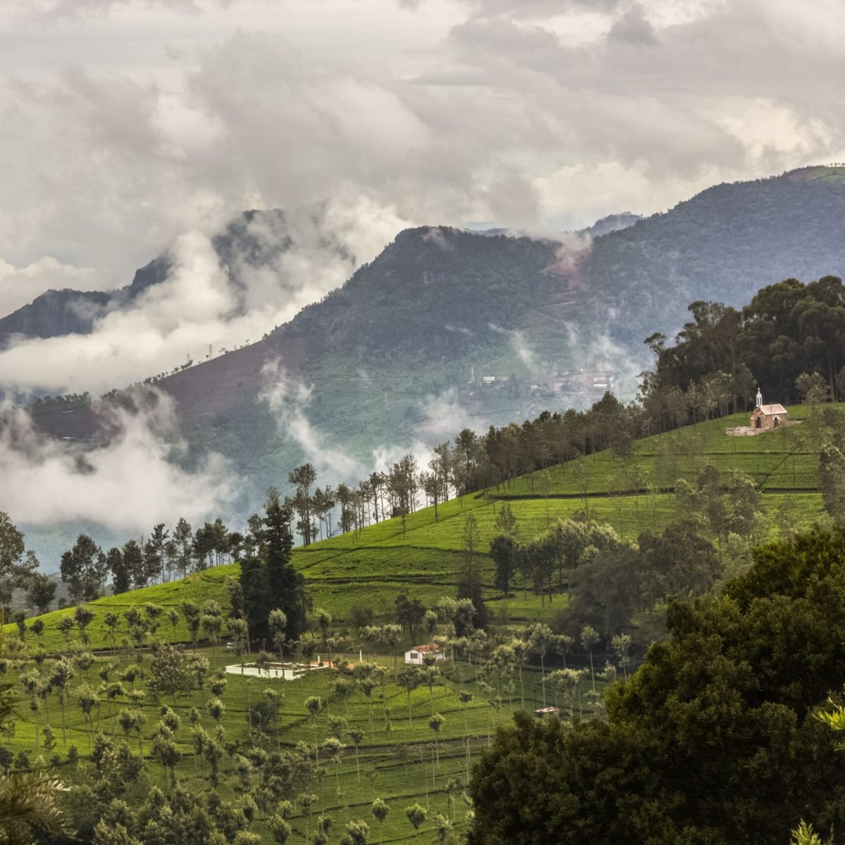 Idyllic countryside view with rolling hills, clouds, and lush greenery, perfect for nature lovers.